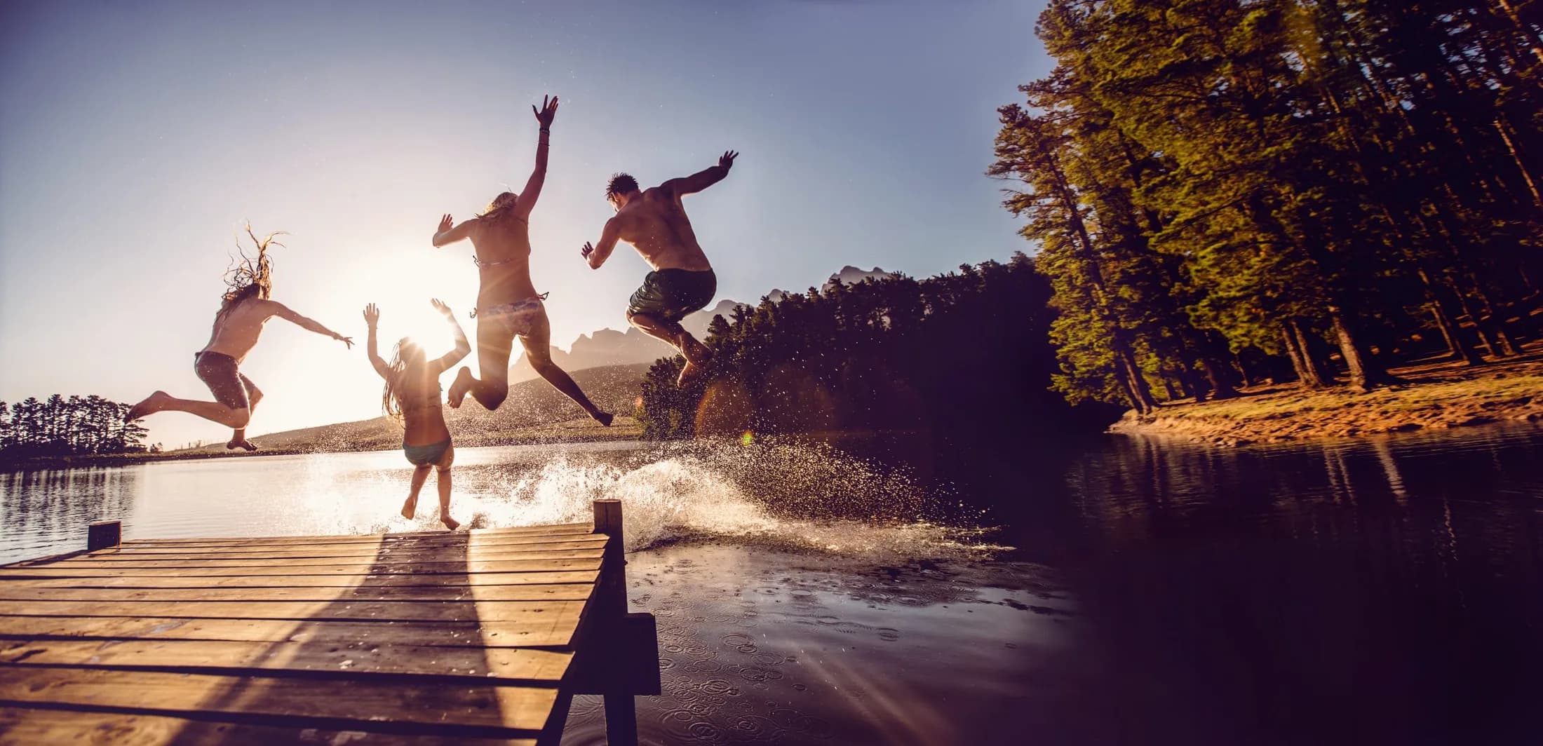 Menschen springen an einem sonnigen Tag in einen See
